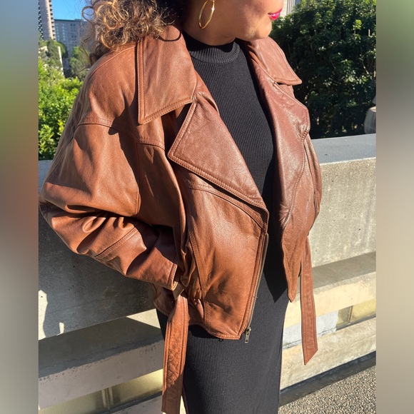 Vintage Brown leather moto jacket with zipper closure and belt detail.